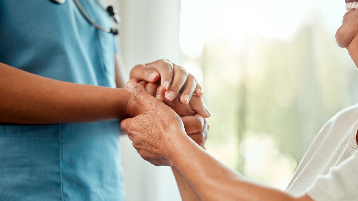 Nurse holding hand of elderly woman