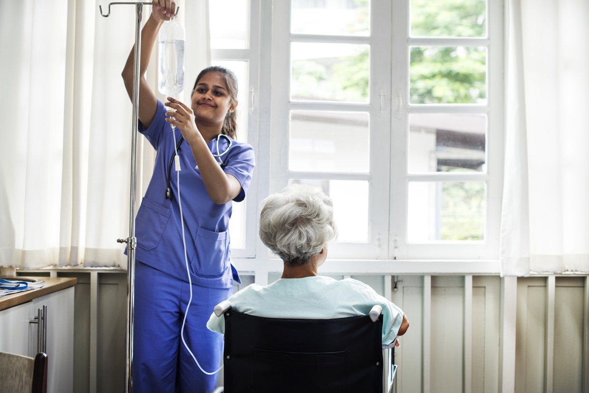 Krankenpflegerin mit älterer Frau im Rollstuhl