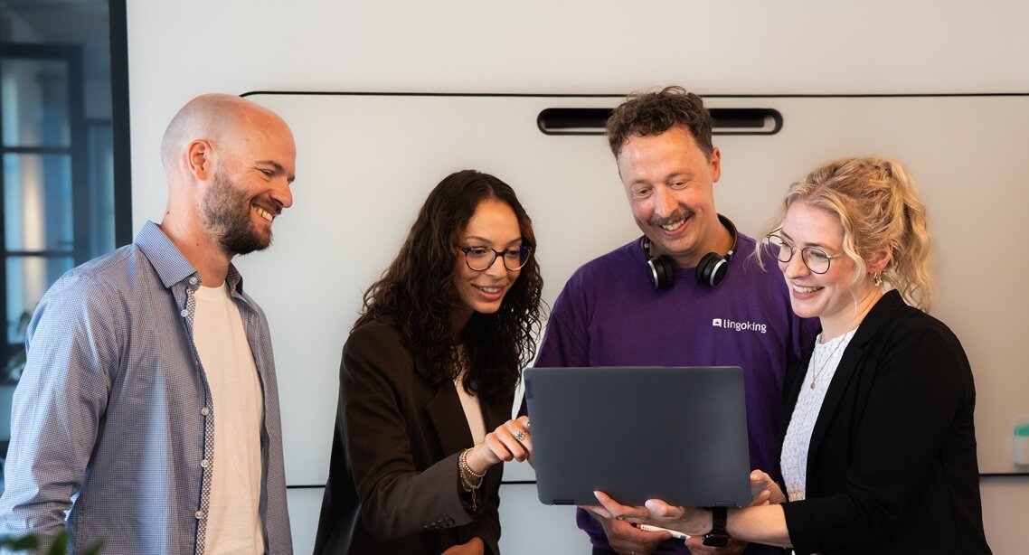 Gruppe Menschen schaut in Laptopn und lächelt