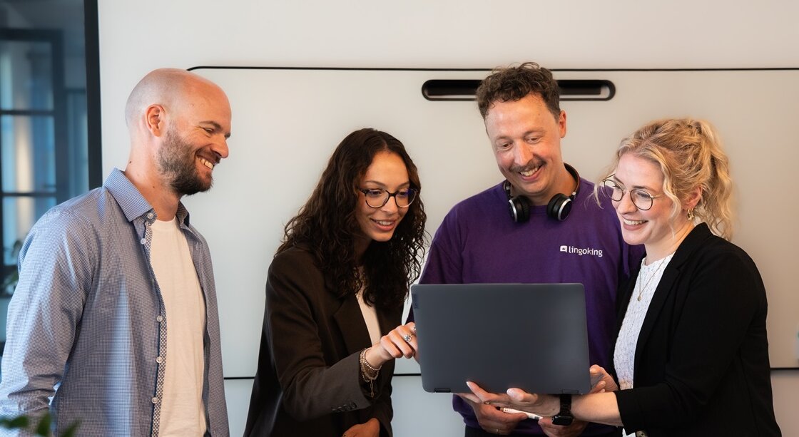 Group of people looing into laptop and smiling