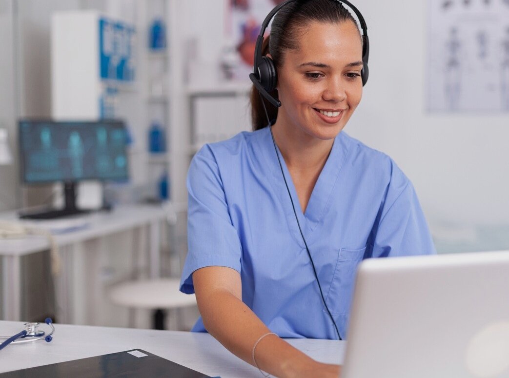 Nurse sitting with headset at laptop