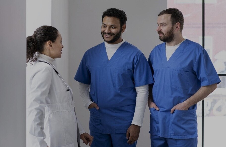 Zwei junge Pflegeauszubildende mit einer Ärztin