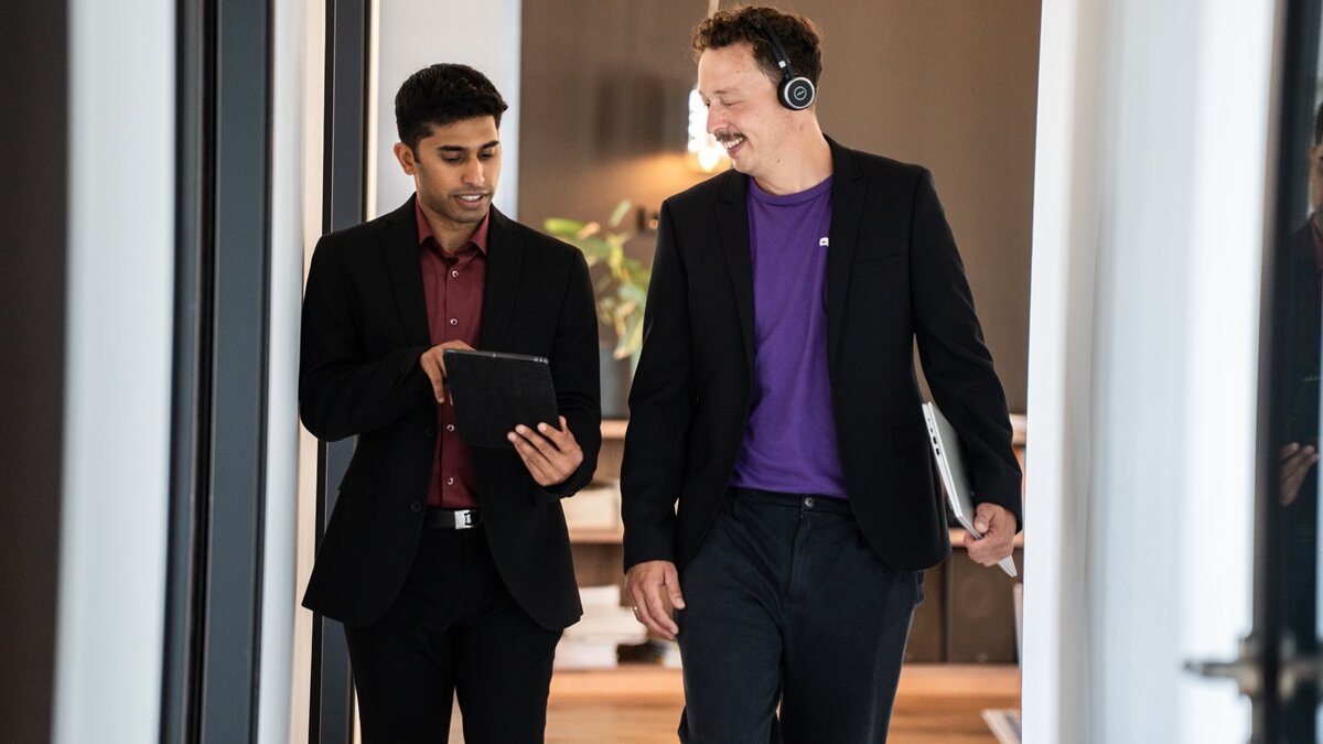 Two people looking into tablet whilst walking
